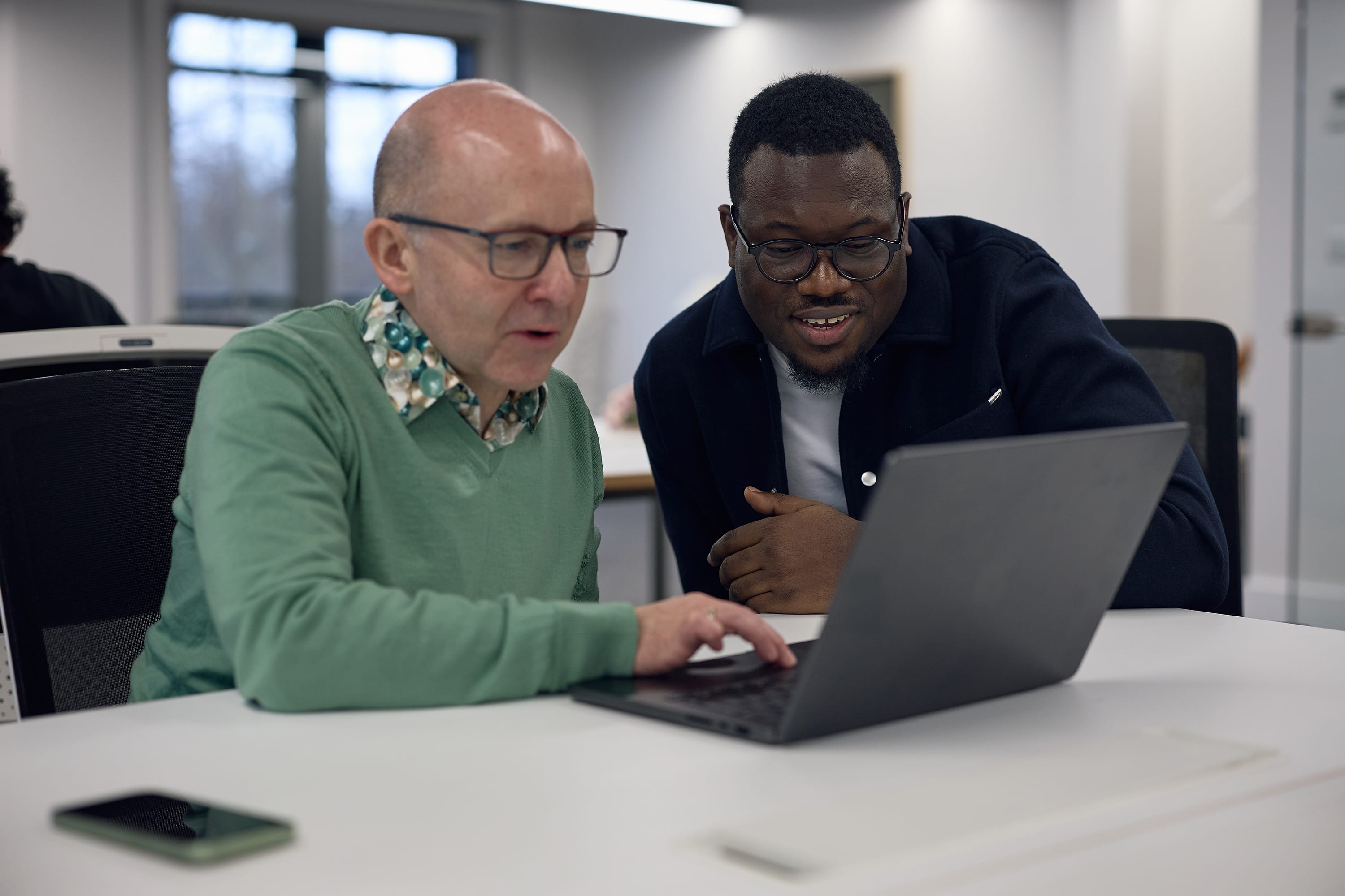 Two colleagues reviewing work together on a laptop in the &above studio